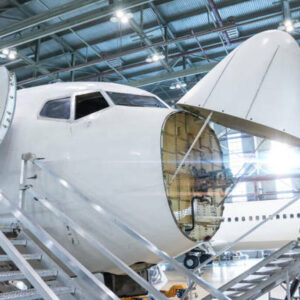 Front view of the white passenger airlines under maintenance in the aviation hangar. The jetliner has opened weather radar. Checking mechanical systems for flight operations